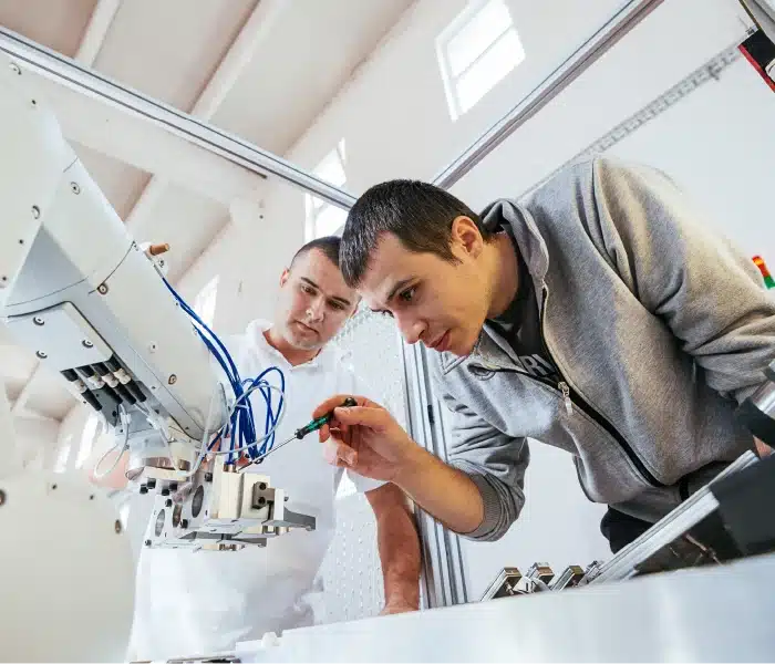 Professor, working with a student on a machine
